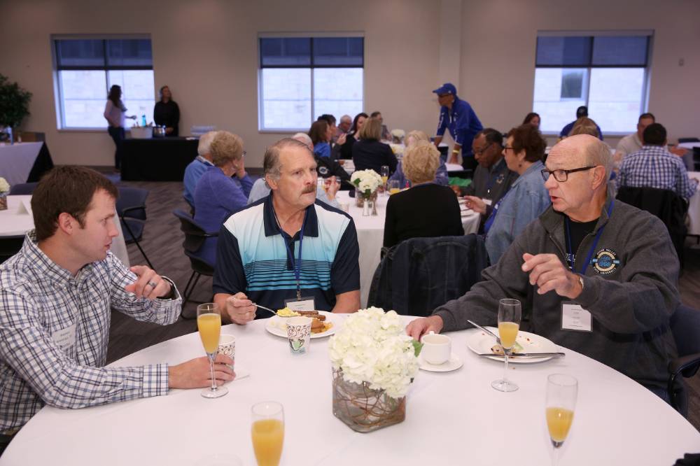 Three alumni enjoying conversation while sipping on a mimosa at the Alumni Brunch.